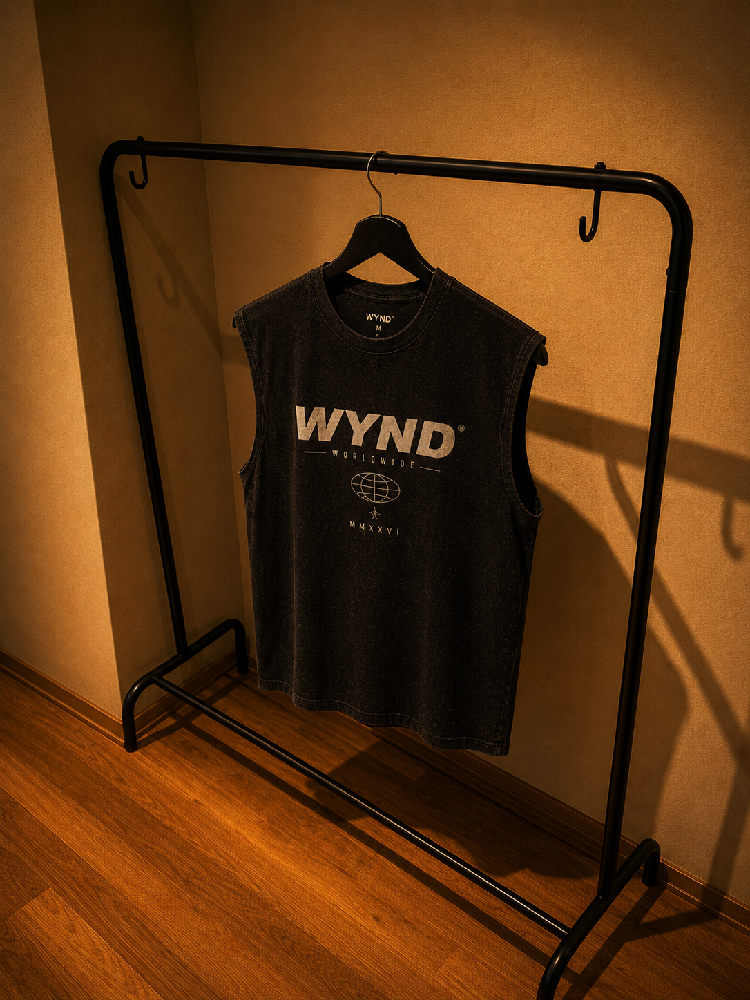 Black sleeveless shirt with 'WYND' logo on a black rack against a beige wall streetwear acid washed
